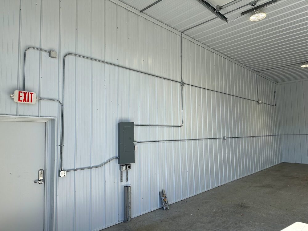 New build shop interior — finished conduit run, panel install, exit lighting