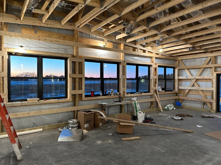 Pole barn rough-in at sunset — framed walls and field view