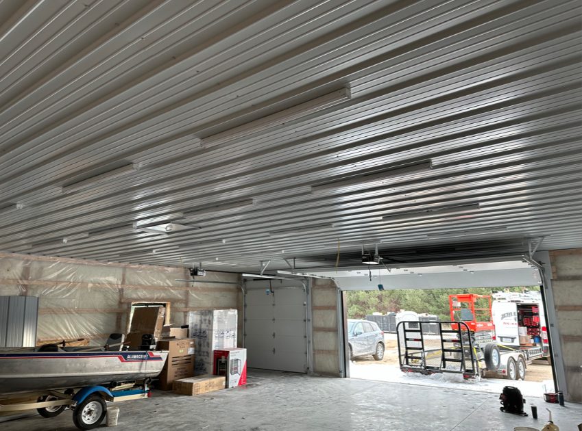 Finished pole barn shop with metal ceiling and overhead garage door