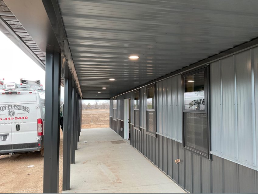 Pole barn covered walkway with lit recessed soffit cans and JETA Electric van