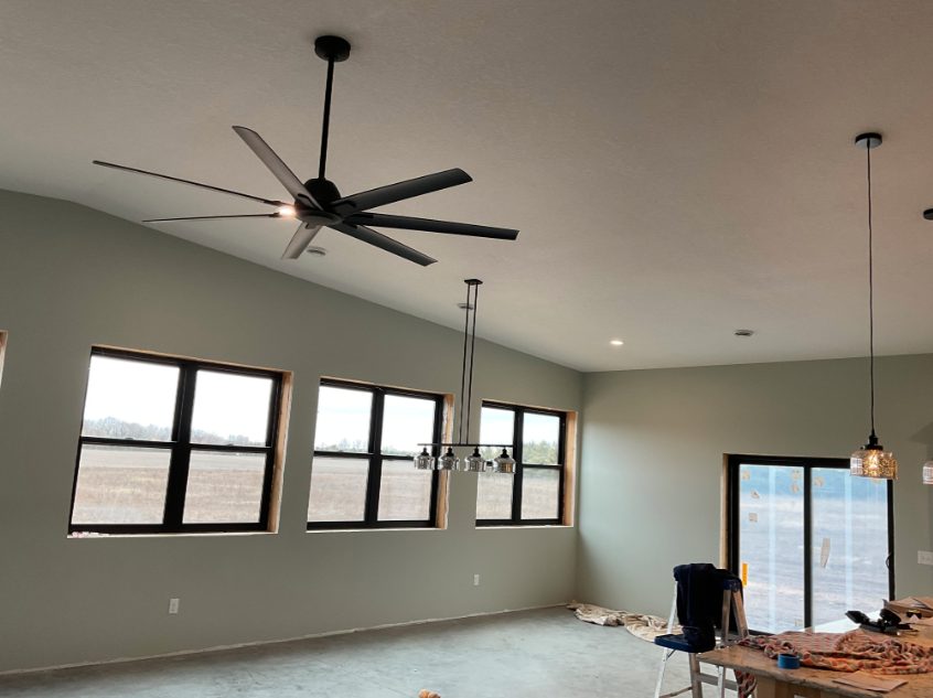 Finished pole barn great room with vaulted ceiling, ceiling fan, and chandelier