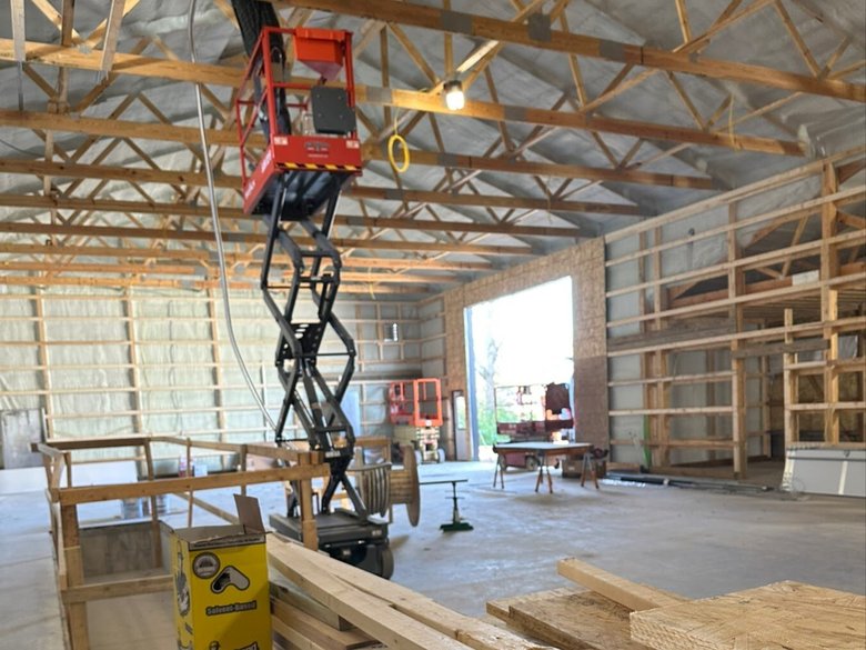 Pole barn interior wired by JETA Electric — scissor lift and roof framing